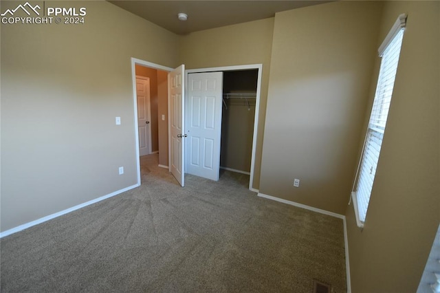 unfurnished bedroom with light carpet and a closet