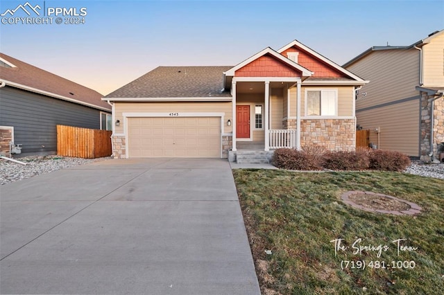 craftsman-style home with a lawn, covered porch, and a garage