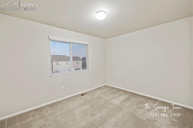 carpeted empty room with a textured ceiling