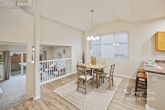 dining space with light hardwood / wood-style floors, lofted ceiling, and a notable chandelier