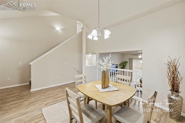 dining room with ceiling fan with notable chandelier, high vaulted ceiling, and light hardwood / wood-style flooring