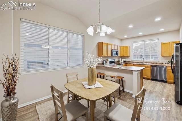 dining space with a notable chandelier, lofted ceiling, sink, and light hardwood / wood-style flooring