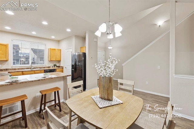 dining area featuring sink, wood-type flooring, and a notable chandelier