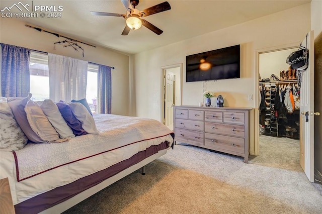 carpeted bedroom featuring a walk in closet, a closet, and ceiling fan