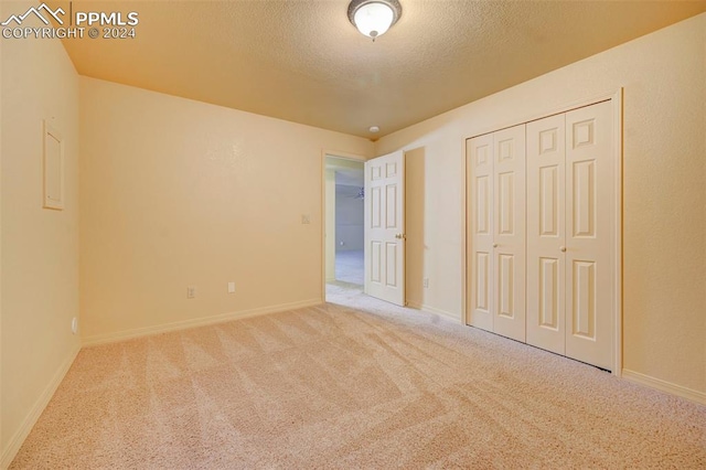 unfurnished bedroom featuring light carpet, a textured ceiling, and a closet