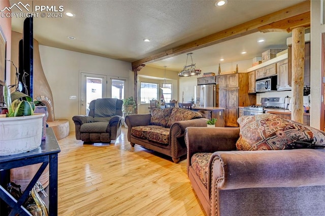 living room with beam ceiling, a textured ceiling, and light hardwood / wood-style flooring