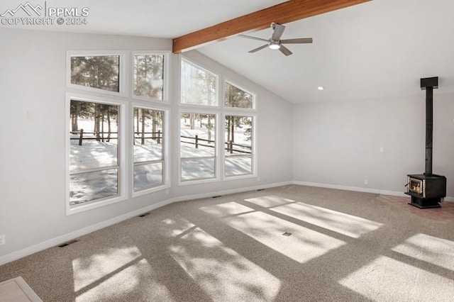 unfurnished living room featuring carpet floors, a wood stove, ceiling fan, and beamed ceiling