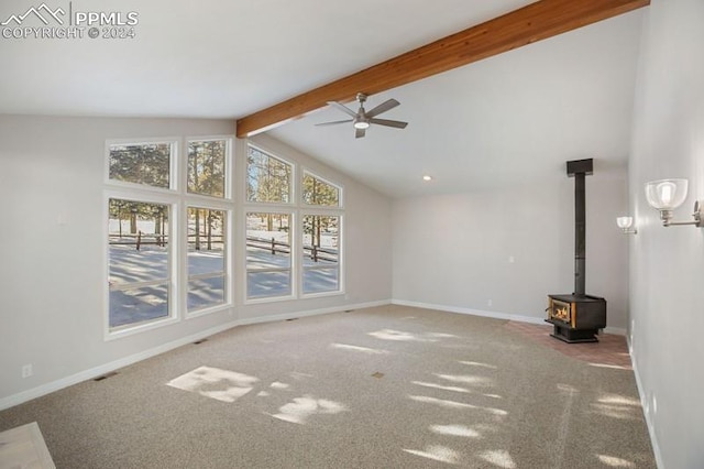 unfurnished living room with carpet flooring, a wood stove, ceiling fan, and lofted ceiling with beams