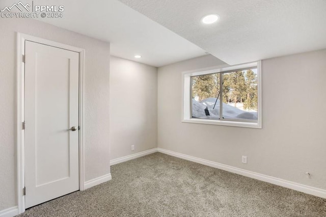 unfurnished room with a textured ceiling and light carpet