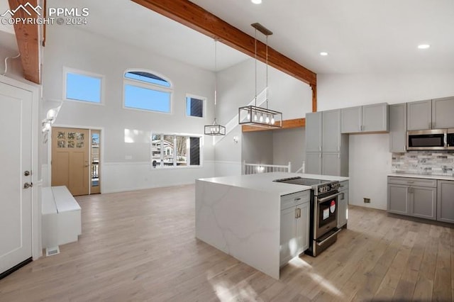 kitchen with appliances with stainless steel finishes, high vaulted ceiling, hanging light fixtures, and beam ceiling