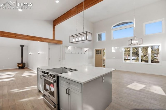 kitchen featuring a wood stove, hanging light fixtures, beamed ceiling, high vaulted ceiling, and stainless steel electric range