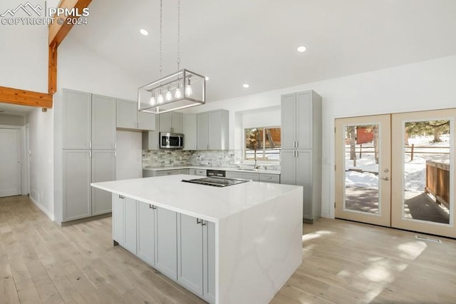 kitchen featuring french doors, light hardwood / wood-style floors, a center island, gray cabinets, and hanging light fixtures