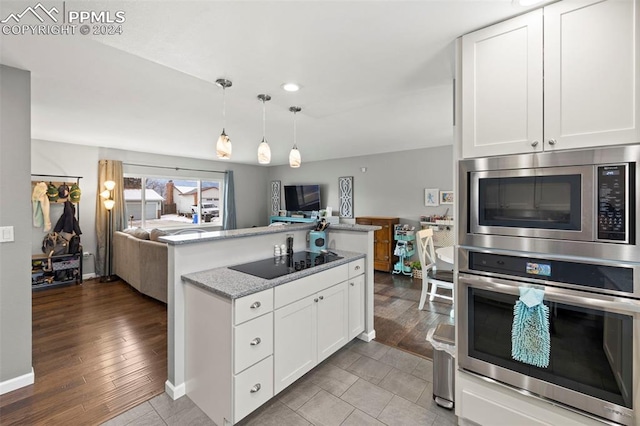 kitchen with white cabinets, appliances with stainless steel finishes, light hardwood / wood-style flooring, and light stone counters