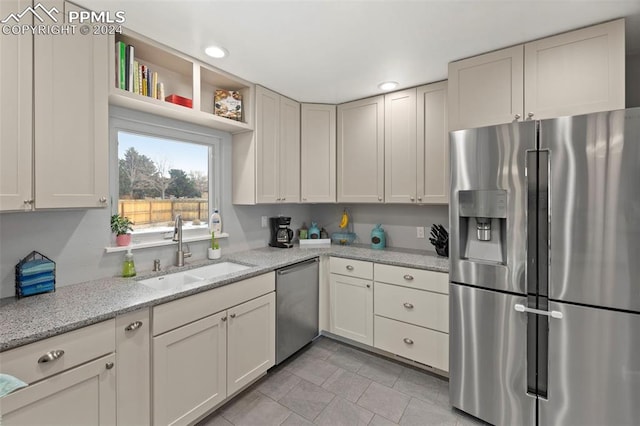 kitchen featuring light stone countertops, sink, and appliances with stainless steel finishes