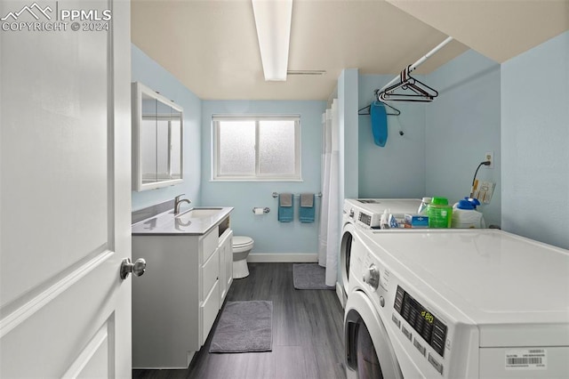 clothes washing area with washer and dryer, dark hardwood / wood-style floors, and sink