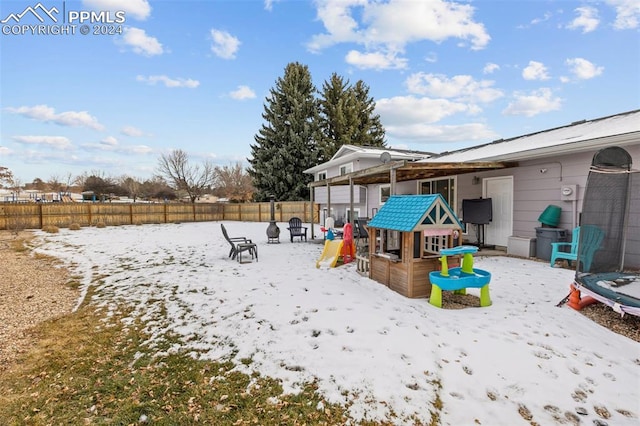 yard covered in snow featuring a playground and a trampoline