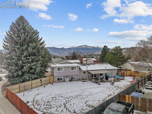 snow covered back of property with a mountain view