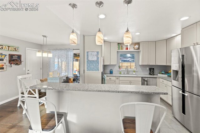 kitchen featuring light stone countertops, sink, stainless steel appliances, a breakfast bar, and white cabinets