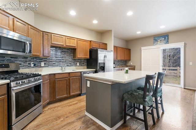 kitchen with tasteful backsplash, a kitchen breakfast bar, light hardwood / wood-style floors, a kitchen island, and appliances with stainless steel finishes