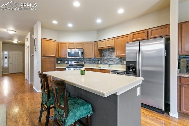 kitchen featuring stainless steel appliances, light hardwood / wood-style flooring, a breakfast bar area, decorative backsplash, and a kitchen island