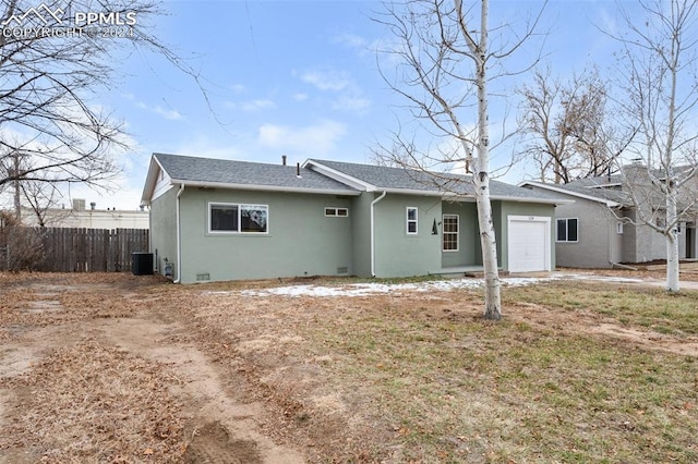 back of house featuring a garage, a lawn, and central air condition unit