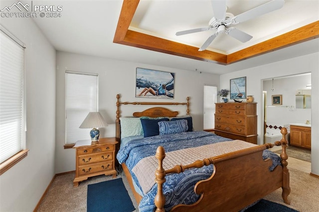 bedroom with connected bathroom, a tray ceiling, ceiling fan, and carpet floors