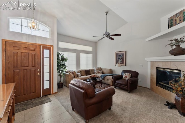 living room featuring plenty of natural light, light tile patterned floors, ceiling fan with notable chandelier, and a tile fireplace