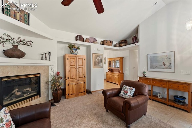 living area with ceiling fan, vaulted ceiling, light tile patterned flooring, and a tiled fireplace