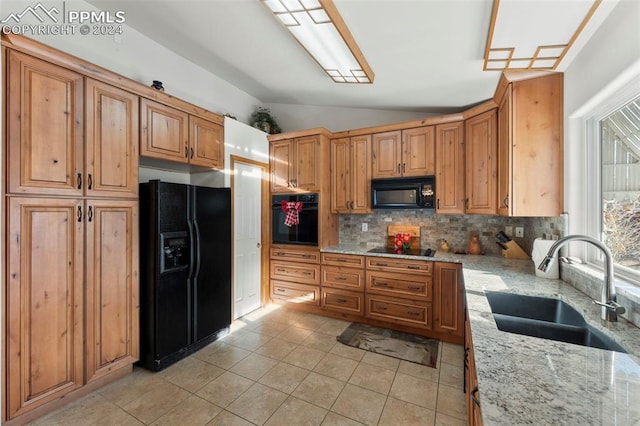 kitchen with decorative backsplash, light stone countertops, sink, black appliances, and lofted ceiling