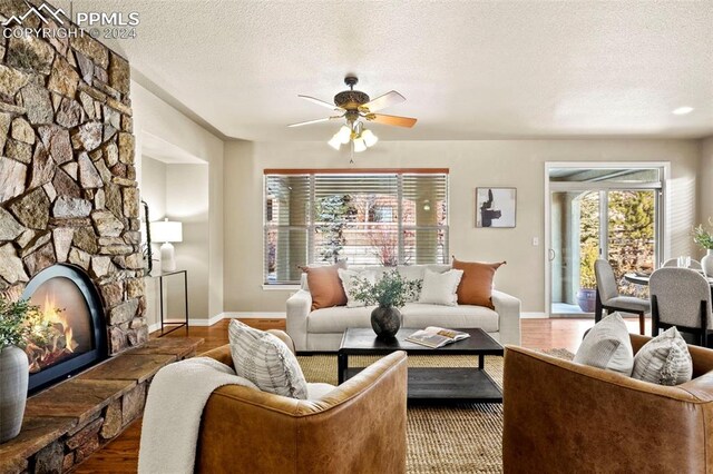 living room with a fireplace, dark hardwood / wood-style floors, a textured ceiling, and ceiling fan