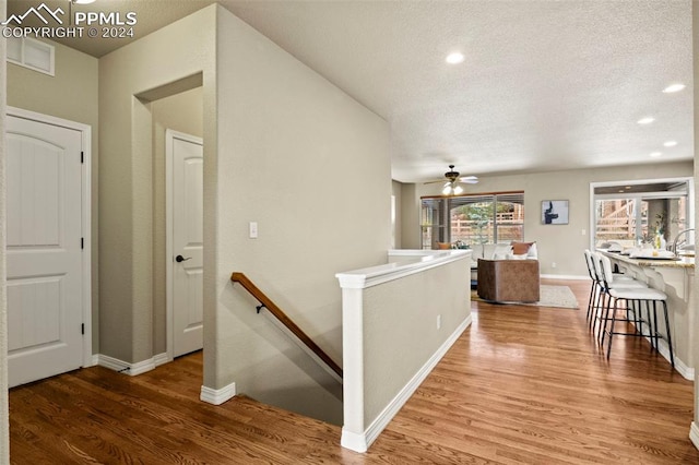 corridor featuring a textured ceiling and hardwood / wood-style flooring