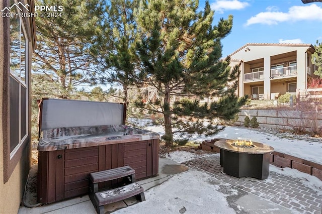 snow covered patio with a hot tub and an outdoor fire pit