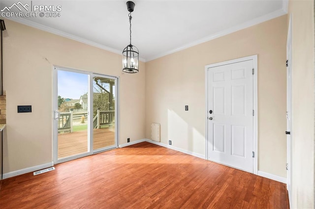 unfurnished dining area featuring hardwood / wood-style floors, a chandelier, and ornamental molding