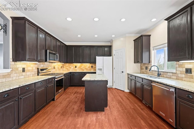 kitchen featuring sink, ornamental molding, appliances with stainless steel finishes, a kitchen island, and dark hardwood / wood-style flooring