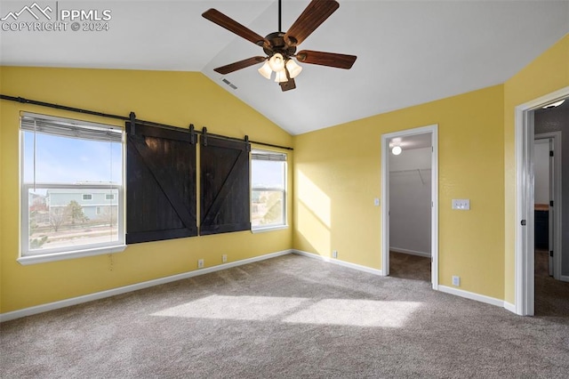 unfurnished bedroom featuring ceiling fan, lofted ceiling, a walk in closet, a closet, and carpet