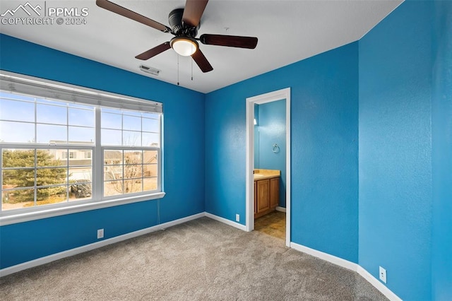 unfurnished bedroom featuring light carpet, ensuite bath, and ceiling fan