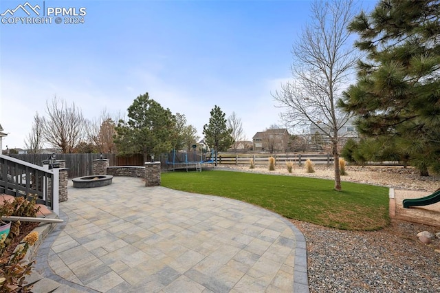 view of patio with a trampoline and an outdoor fire pit