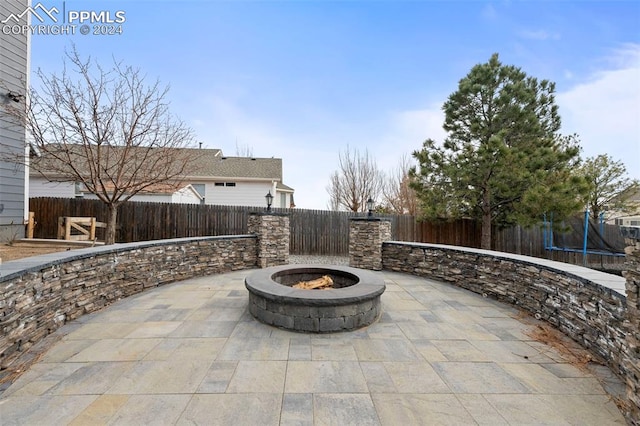 view of patio with an outdoor fire pit and a trampoline