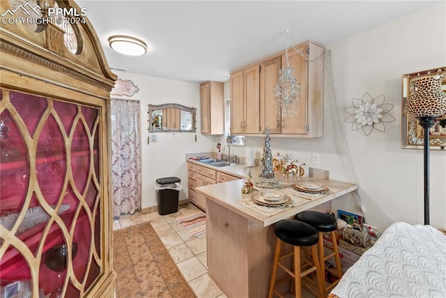 kitchen with kitchen peninsula, light brown cabinetry, sink, a breakfast bar area, and light tile patterned flooring