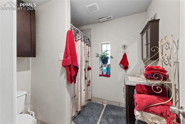 bathroom with a shower with shower curtain, tile patterned floors, vanity, and toilet