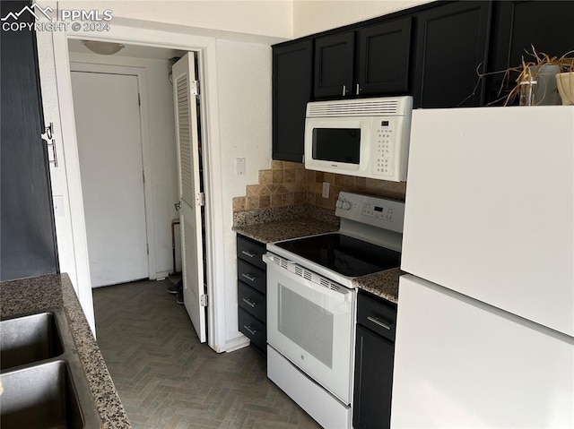 kitchen with dark parquet flooring, sink, backsplash, dark stone counters, and white appliances