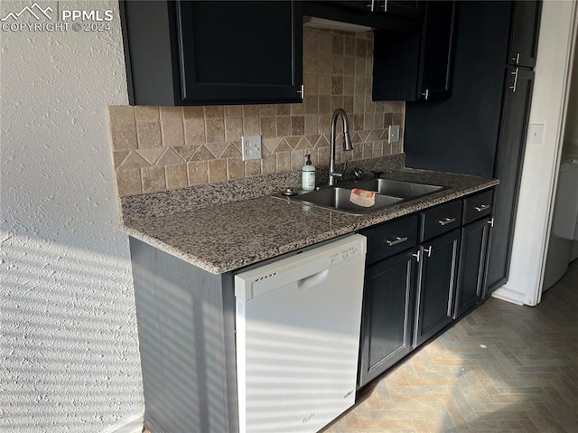 kitchen with sink, parquet flooring, white dishwasher, dark stone counters, and decorative backsplash