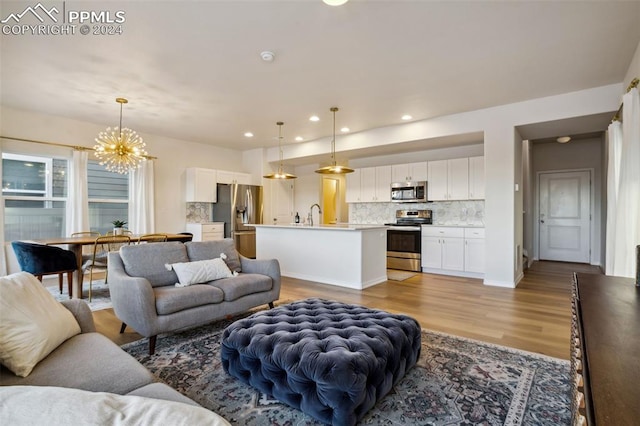 living room with a notable chandelier, light wood-type flooring, and sink