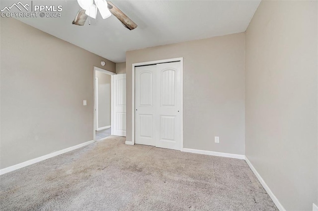 unfurnished bedroom with ceiling fan, a closet, and carpet floors