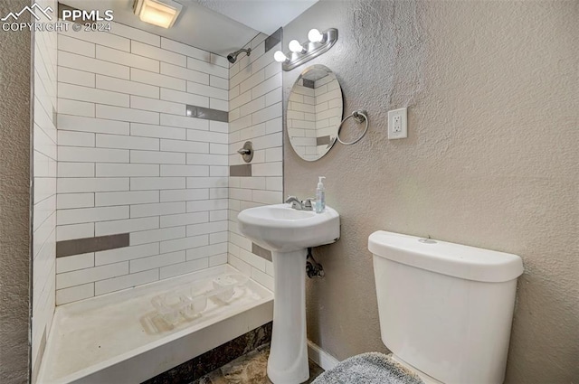 bathroom with a tile shower and toilet