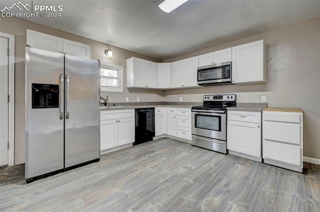 kitchen featuring stainless steel appliances, white cabinetry, light hardwood / wood-style floors, and sink