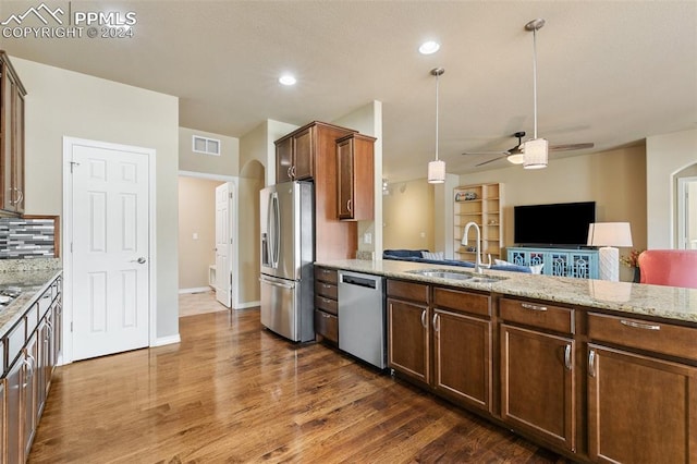 kitchen featuring light stone countertops, dark hardwood / wood-style flooring, stainless steel appliances, sink, and pendant lighting