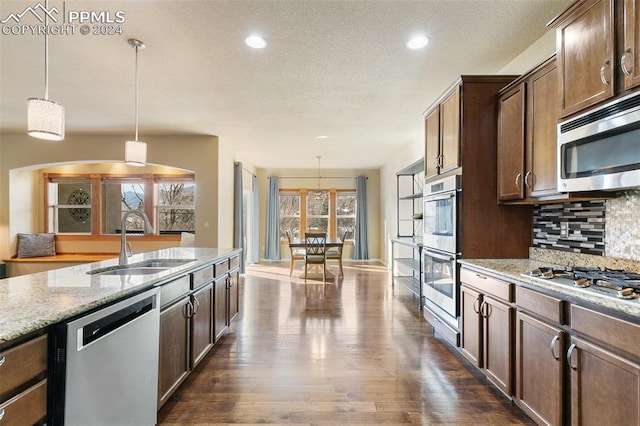 kitchen featuring appliances with stainless steel finishes, a wealth of natural light, and hanging light fixtures