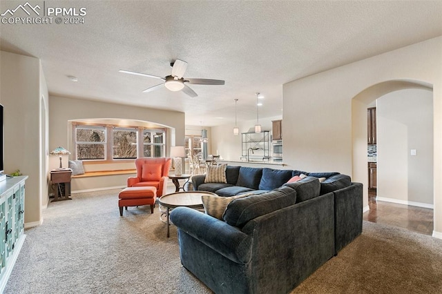 living room featuring ceiling fan, carpet floors, and a textured ceiling