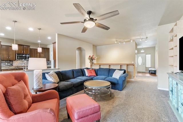 carpeted living room featuring ceiling fan and sink